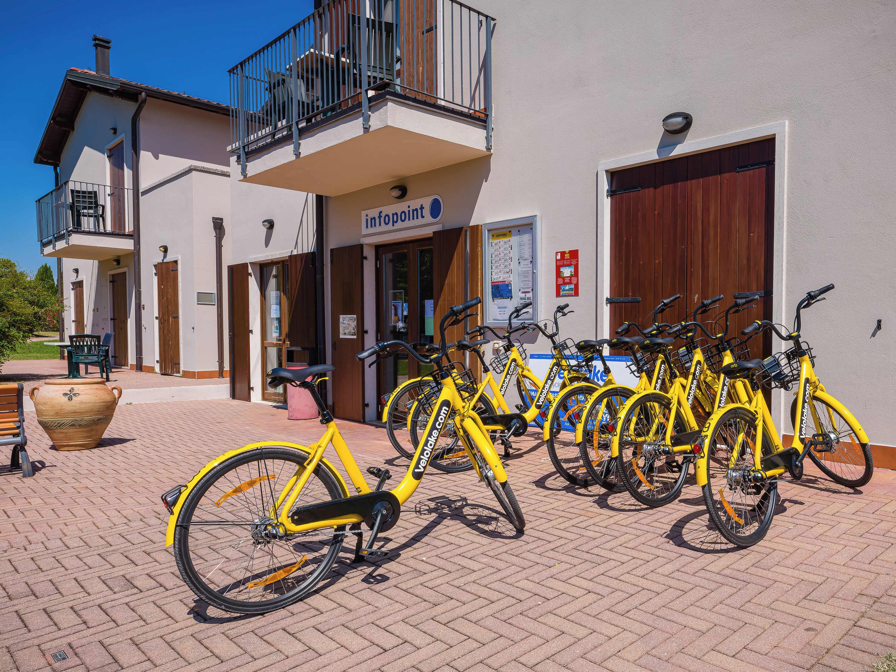 A building with a sign reading 'infopoint' and a row of yellow bicycles parked outside.