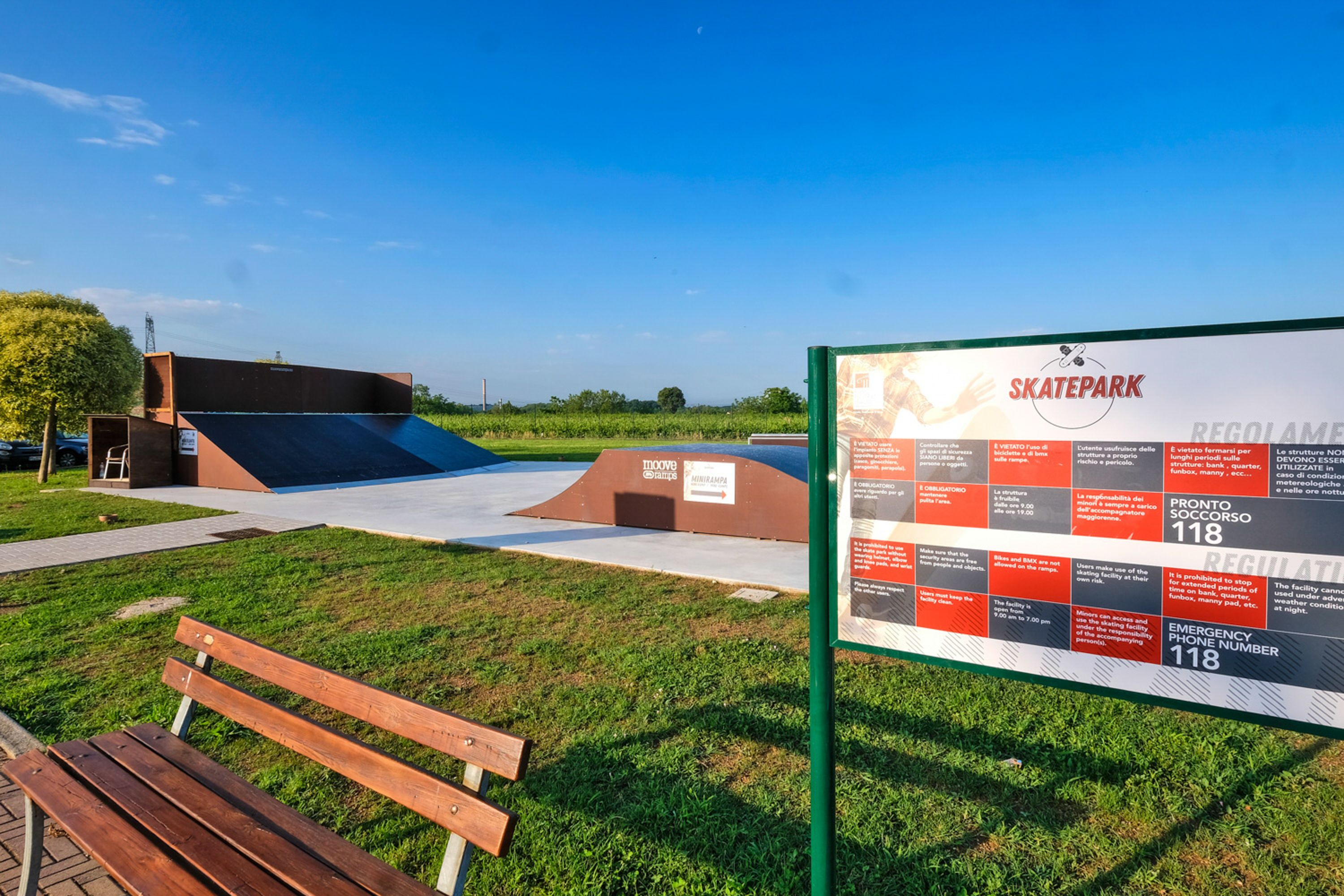 A skatepark with a ramp, benches, and informational signs.