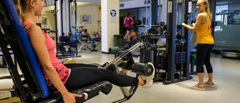 Un gimnasio con equipo de ejercicio, incluyendo una máquina de remo y una máquina de pesas.