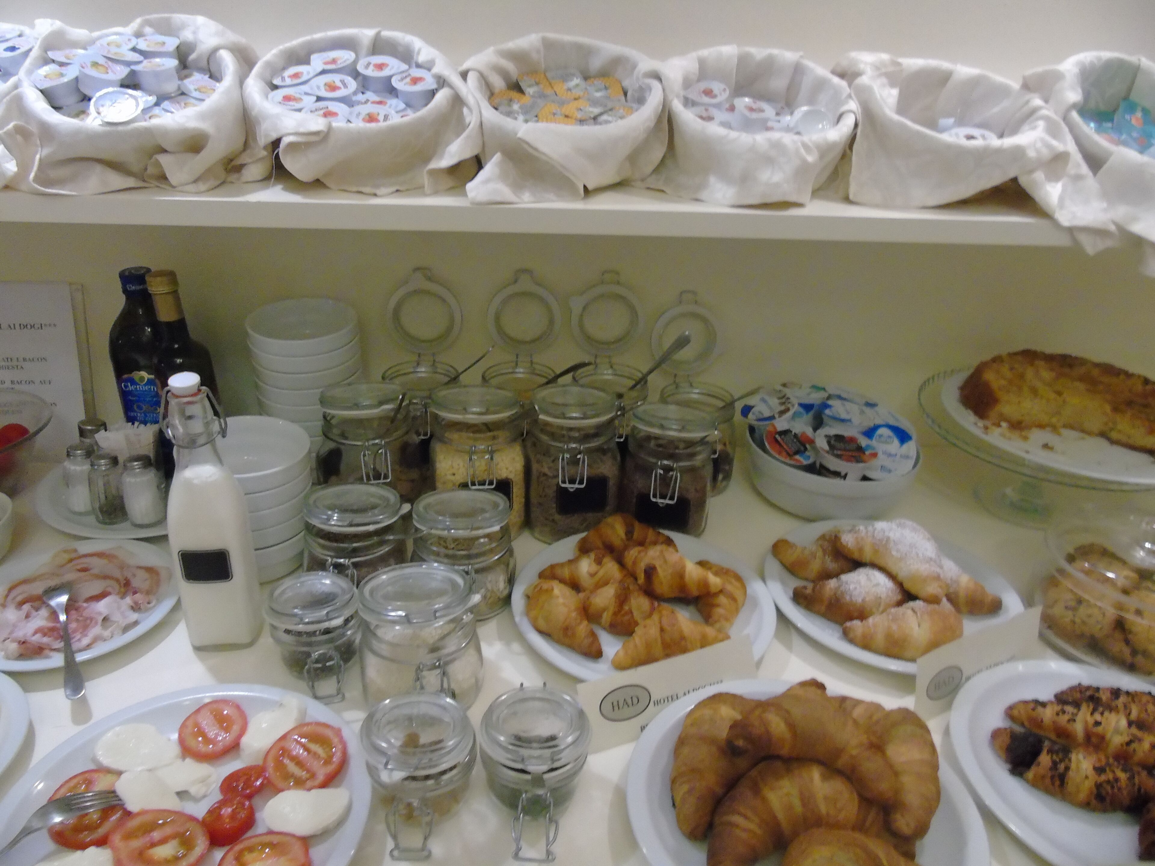 A breakfast buffet with various food items, including croissants, cheese, and condiments.
