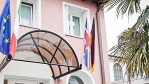 Entrada de hotel con toldo de cristal, varias banderas y un letrero que dice 'HAD HOTEL AL DOGE'.