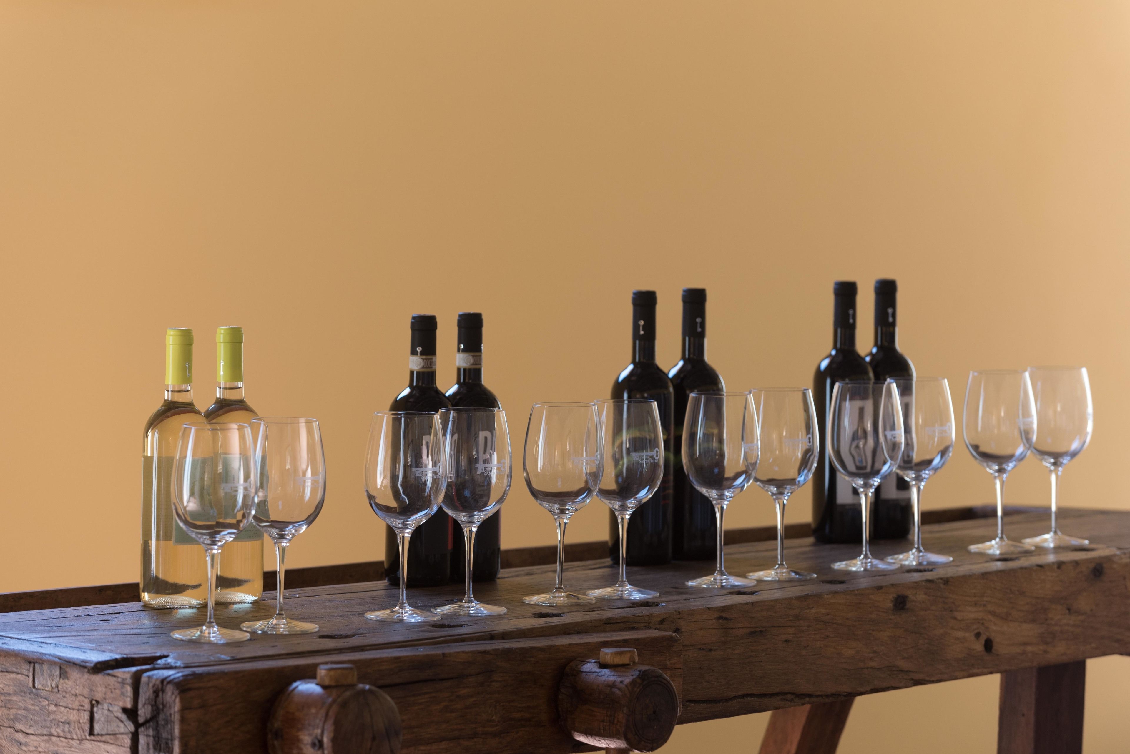 Una mesa de madera con botellas y copas de vino dispuestas sobre ella.