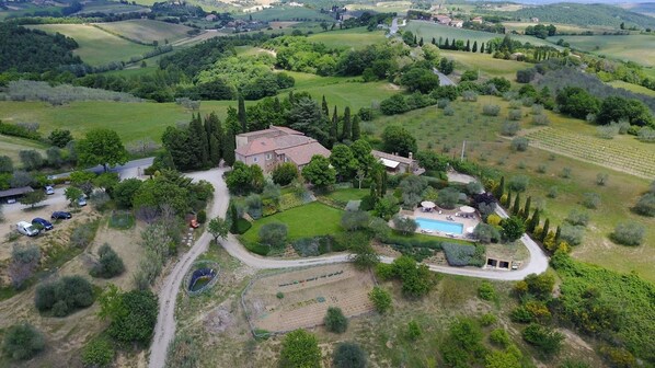 Vista aérea de una propiedad en el campo con una casa grande, piscina y jardines circundantes.