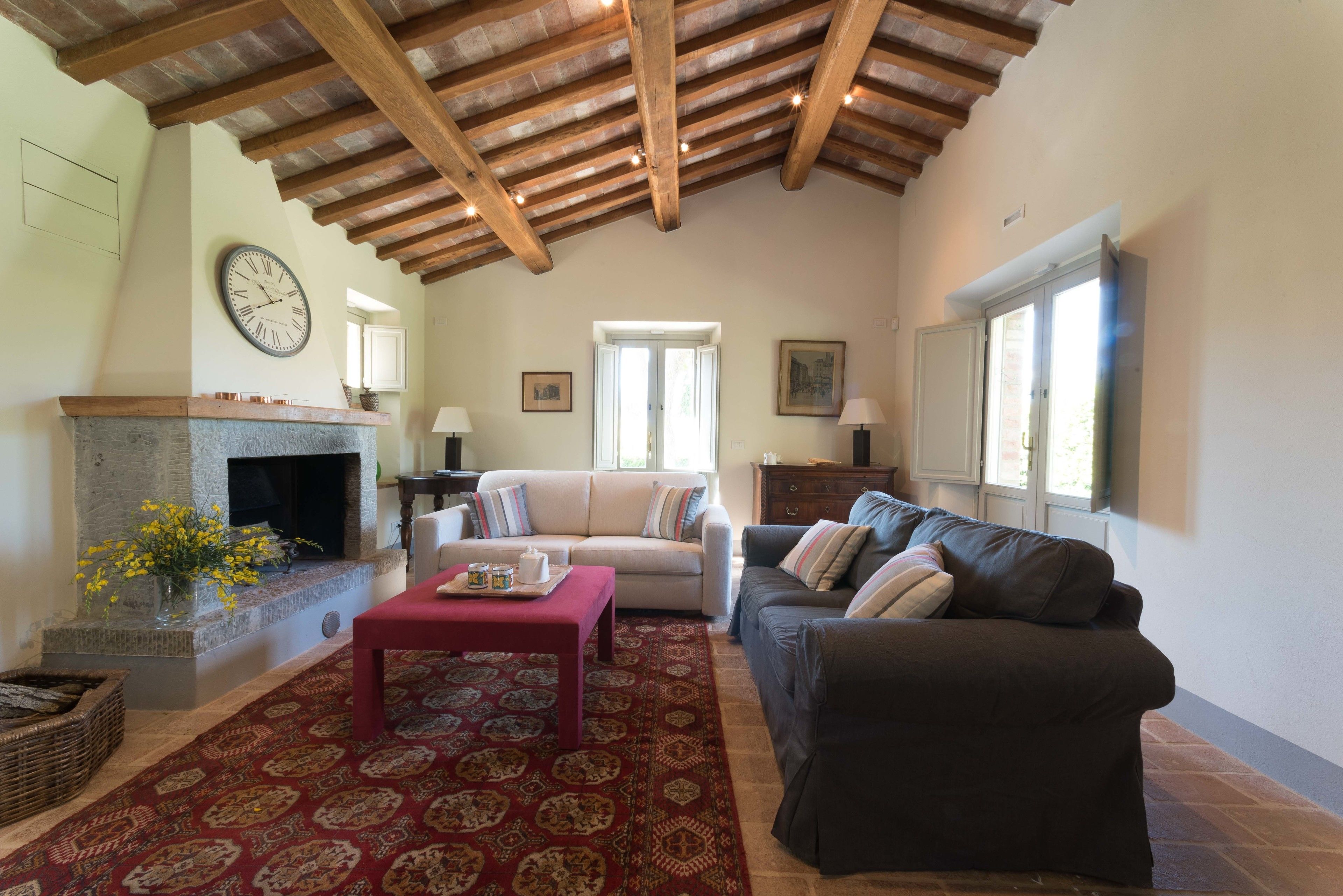 Una sala de estar con chimenea, dos sofás, una mesa de centro y un tapete estampado.