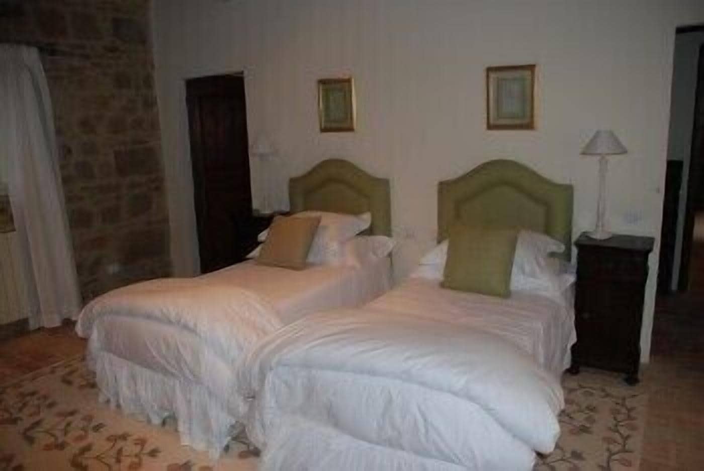 A hotel room with two beds, a nightstand, and a lamp.