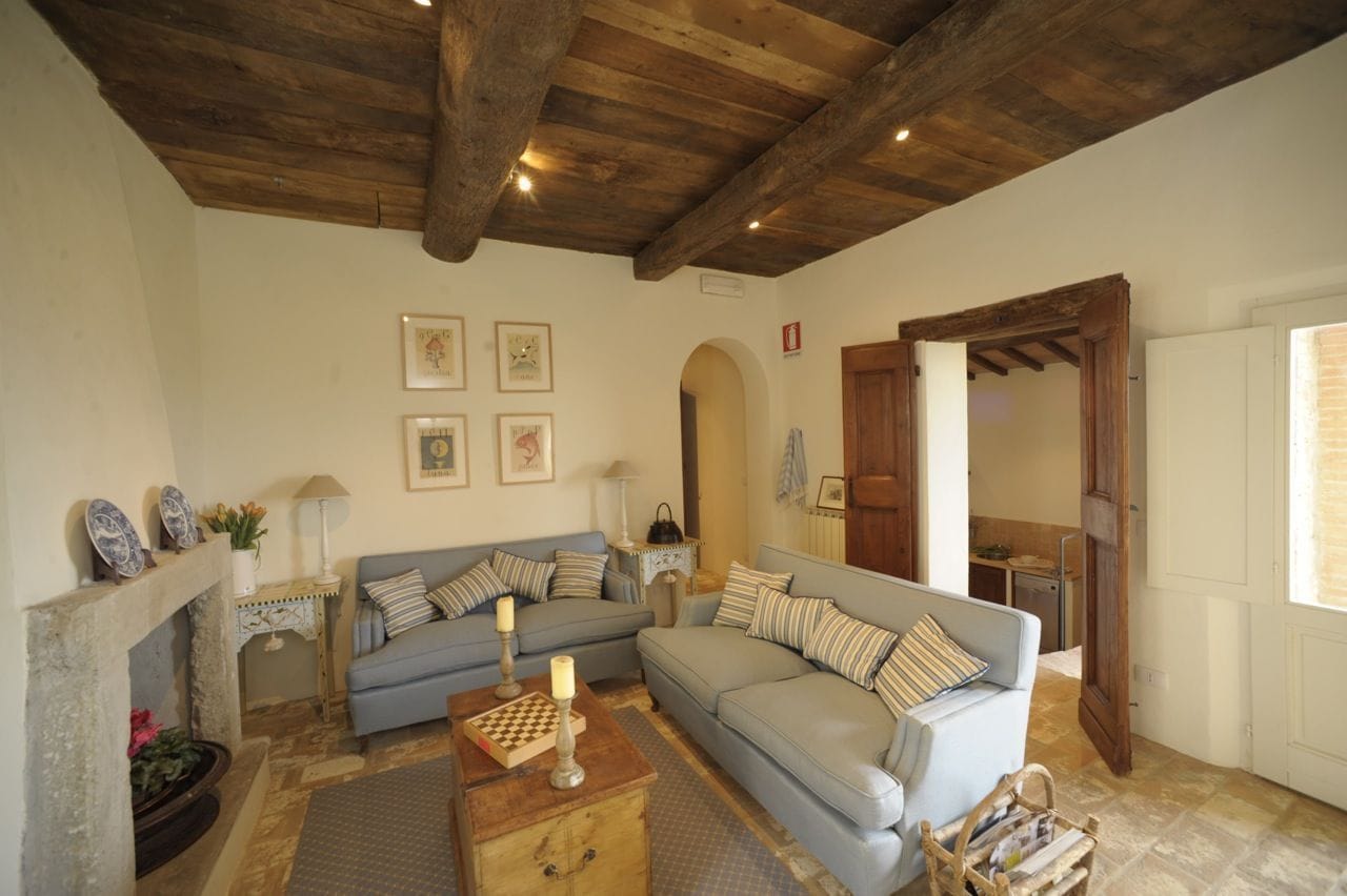 A cozy living room with a fireplace, a blue sofa, a wooden coffee table, and a wooden ceiling.