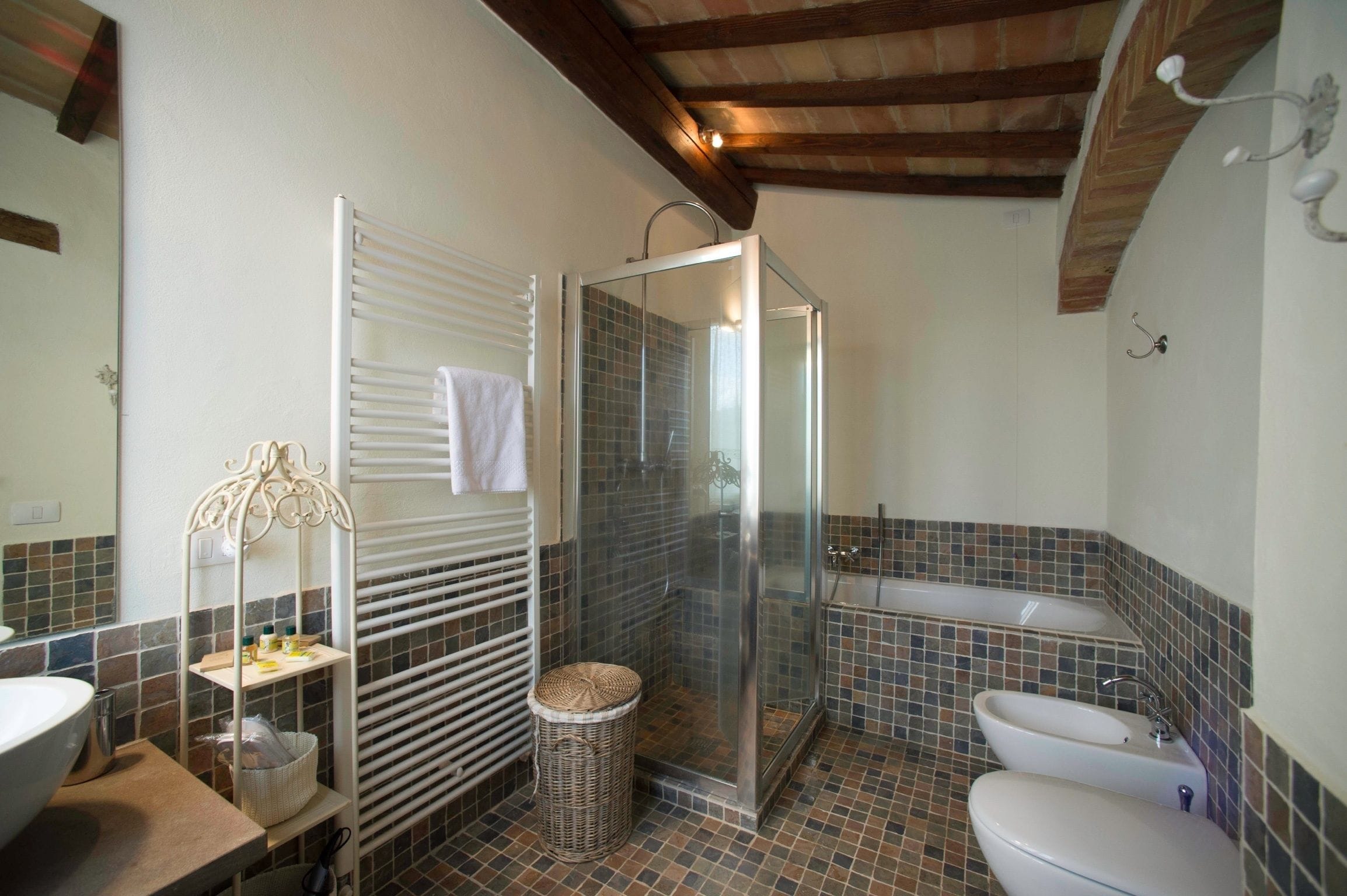 A bathroom with a glass-enclosed shower, a bathtub, and a toilet.