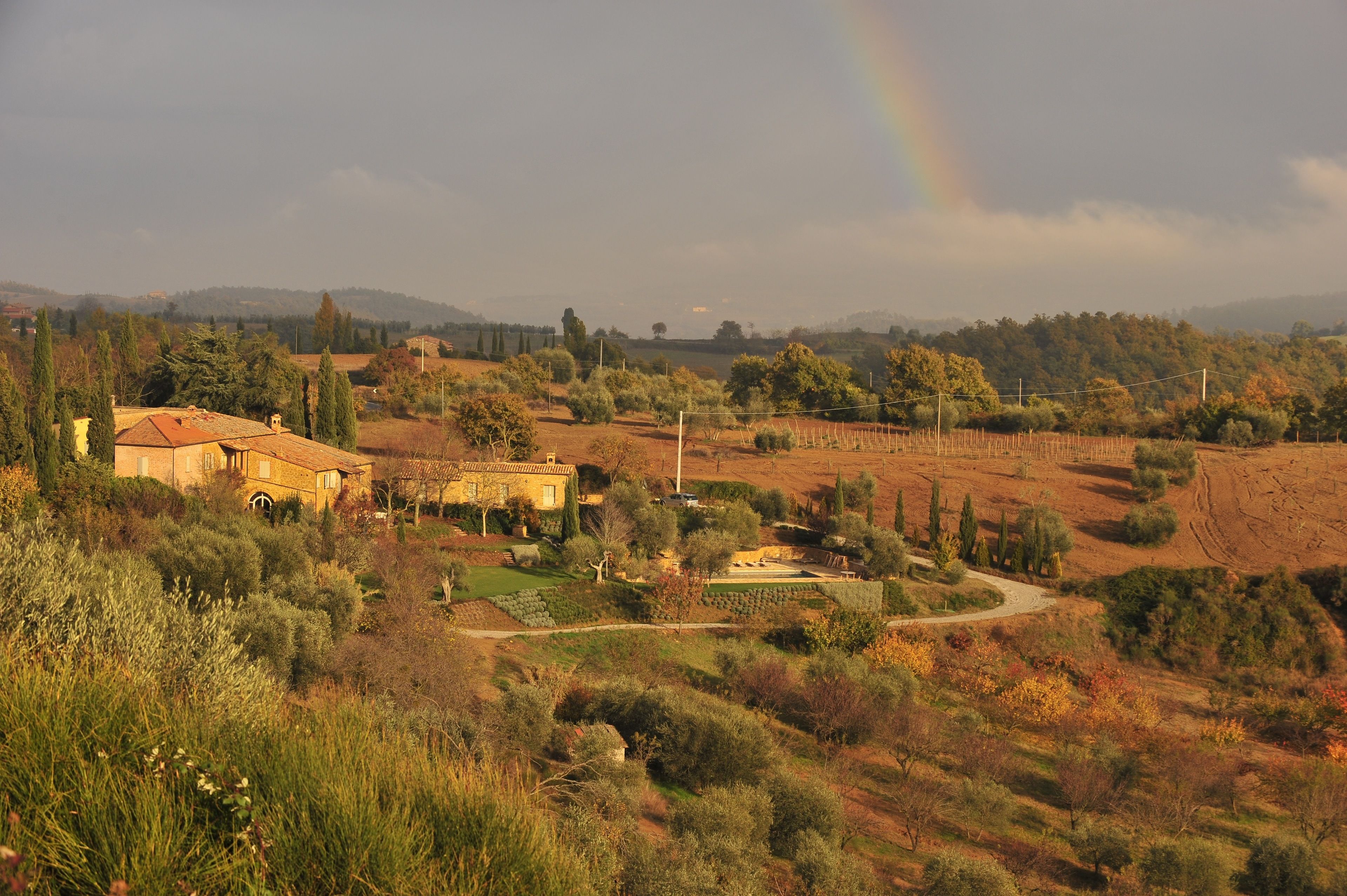 Un paisaje rural con una casa, campos y un arcoíris.