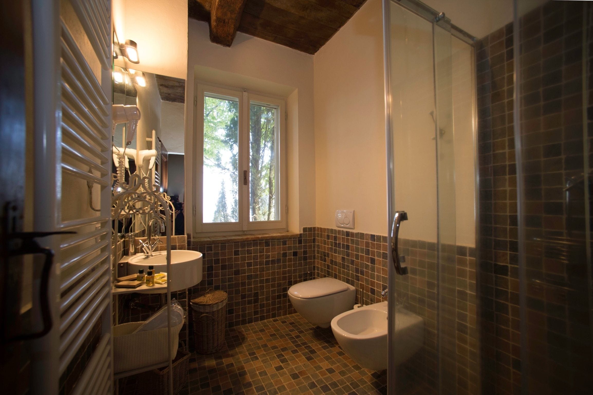 A bathroom with a sink, toilet, bidet, and a glass shower enclosure.