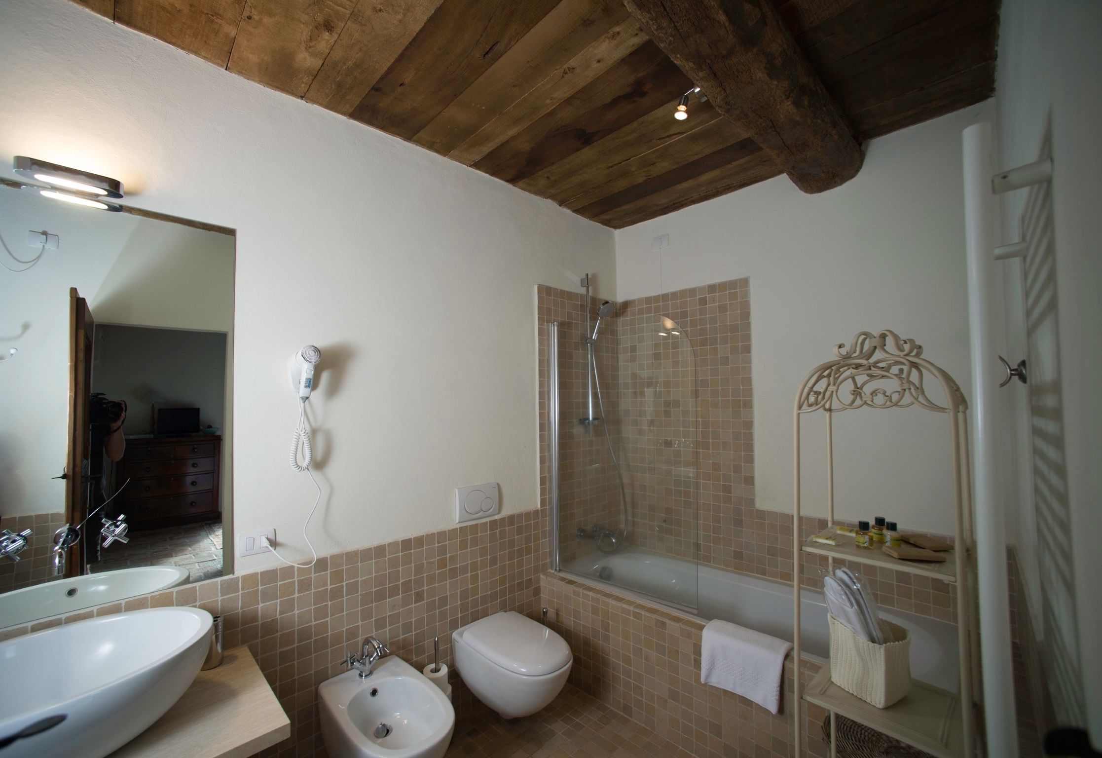 A bathroom with a large mirror, two sinks, a bidet, a shower, and a bathtub.
