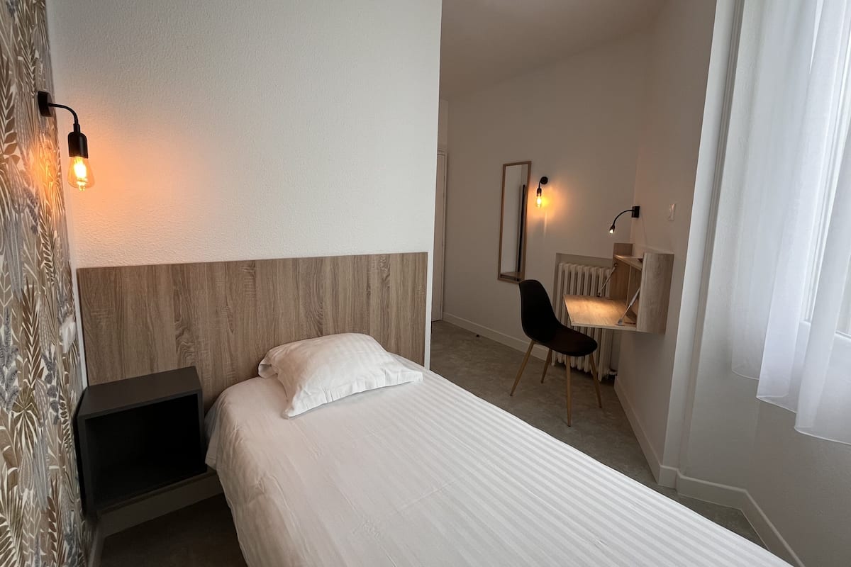 Ein Hotelzimmer mit Bett, Schreibtisch, Stuhl und Heizkörper.