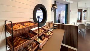 A breakfast buffet with various breads and pastries, a mirror, and a modern interior design. - Hotel Le Keroman (Lorient)