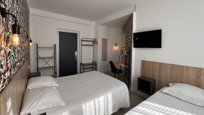 A hotel room with two beds, a desk with a chair, a TV, and a patterned wall. - Hotel Le Keroman (Lorient)