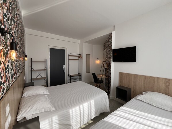 Habitación de hotel con dos camas, un escritorio con silla, televisión y pared con diseño.