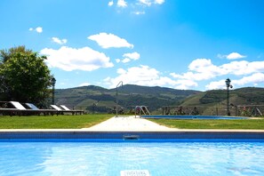 A swimming pool with lounge chairs and a view of hills.