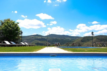 Una piscina al aire libre, sombrillas, sillones reclinables de piscina