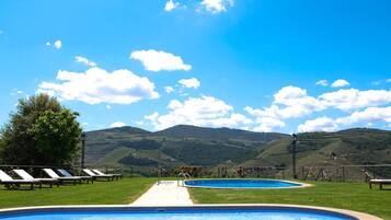 A pool area with lounge chairs and a view of rolling hills.