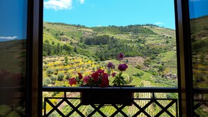 A view from a window with a balcony, overlooking a hilly landscape with terraced fields and a clear blue sky. - Hotel Rural Quinta do Silval (Alijó)