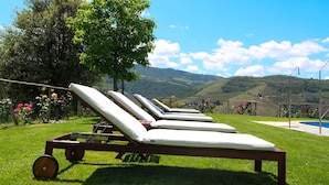 A row of sun loungers with wheels on a grassy lawn, overlooking a scenic valley with hills and a clear sky. - Hotel Rural Quinta do Silval (Alijó)