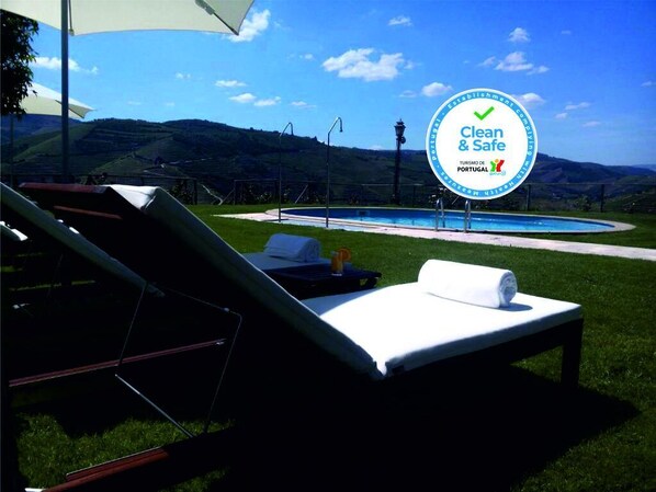 A poolside lounge area with a sign indicating 'Clean & Safe' and 'Turismo de Portugal'.