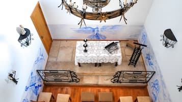 A room with a chandelier, a table with a lace tablecloth, and a mural on the wall.