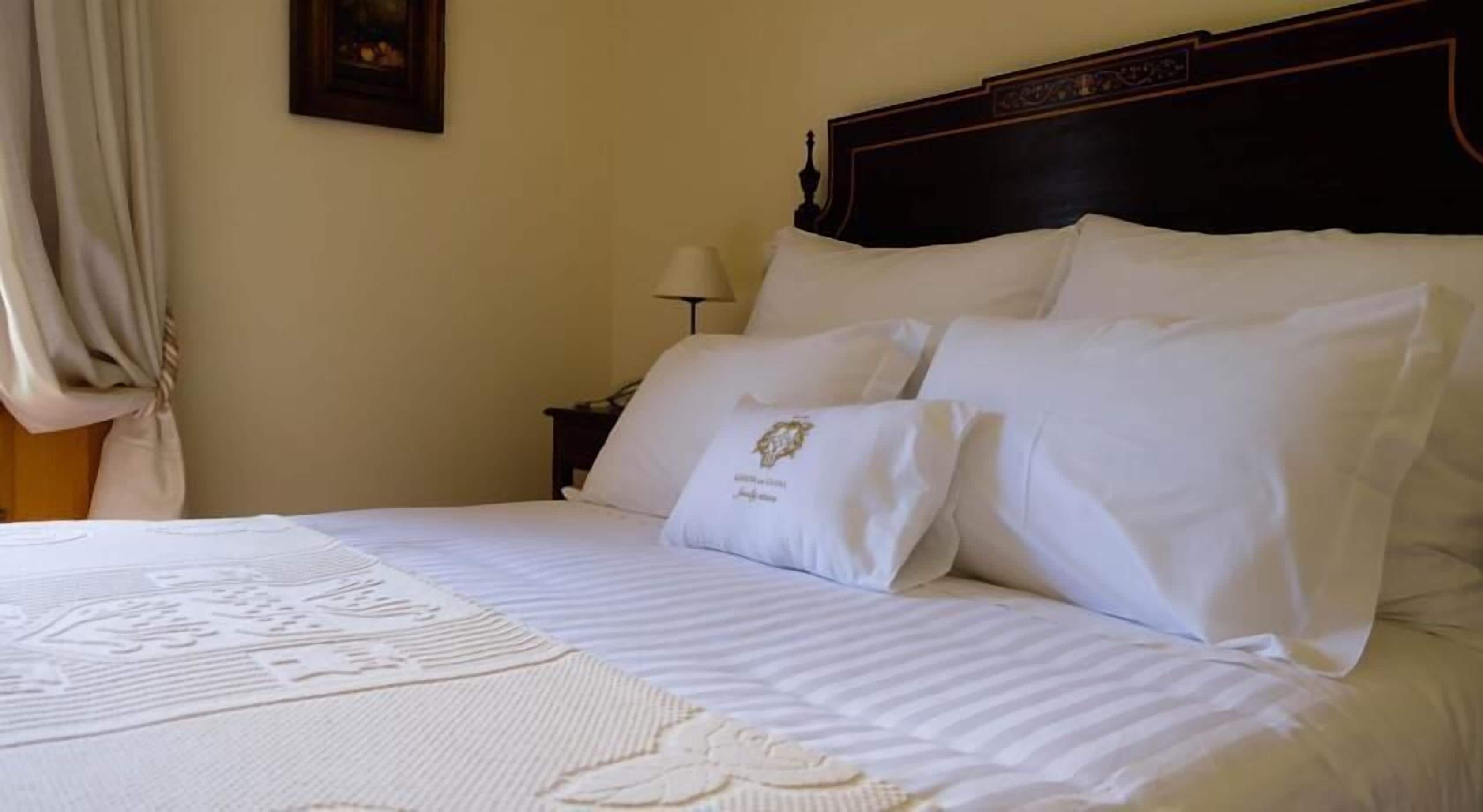 Una cama bien hecha con sábanas blancas y un cojín decorativo.