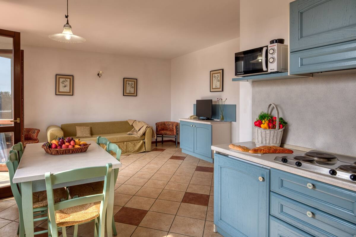 A compact kitchen with a dining area, featuring a stove, microwave, and a television.