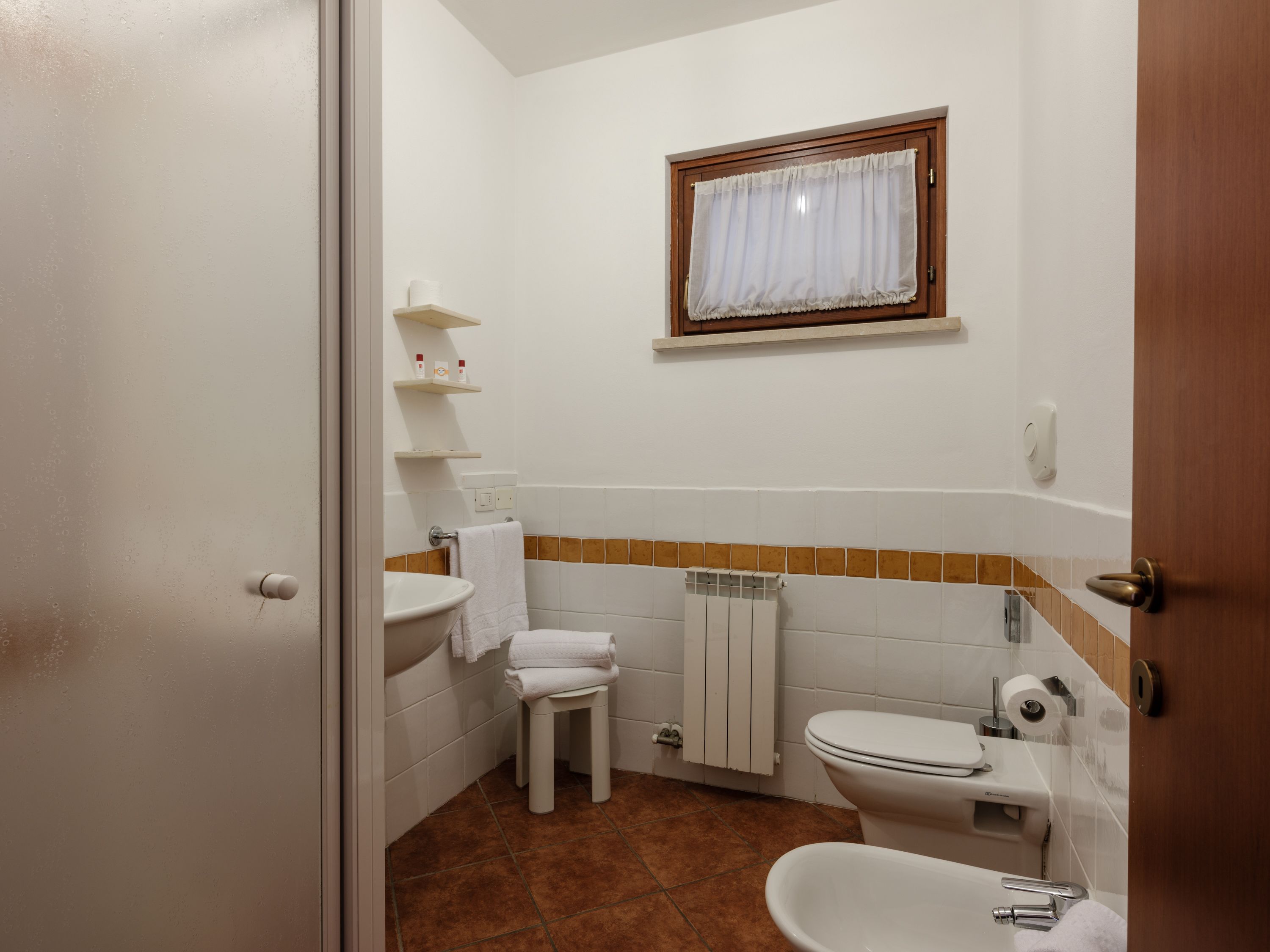 A compact bathroom with a toilet, sink, and a small window.