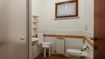 A compact bathroom with a toilet, sink, and a small window.