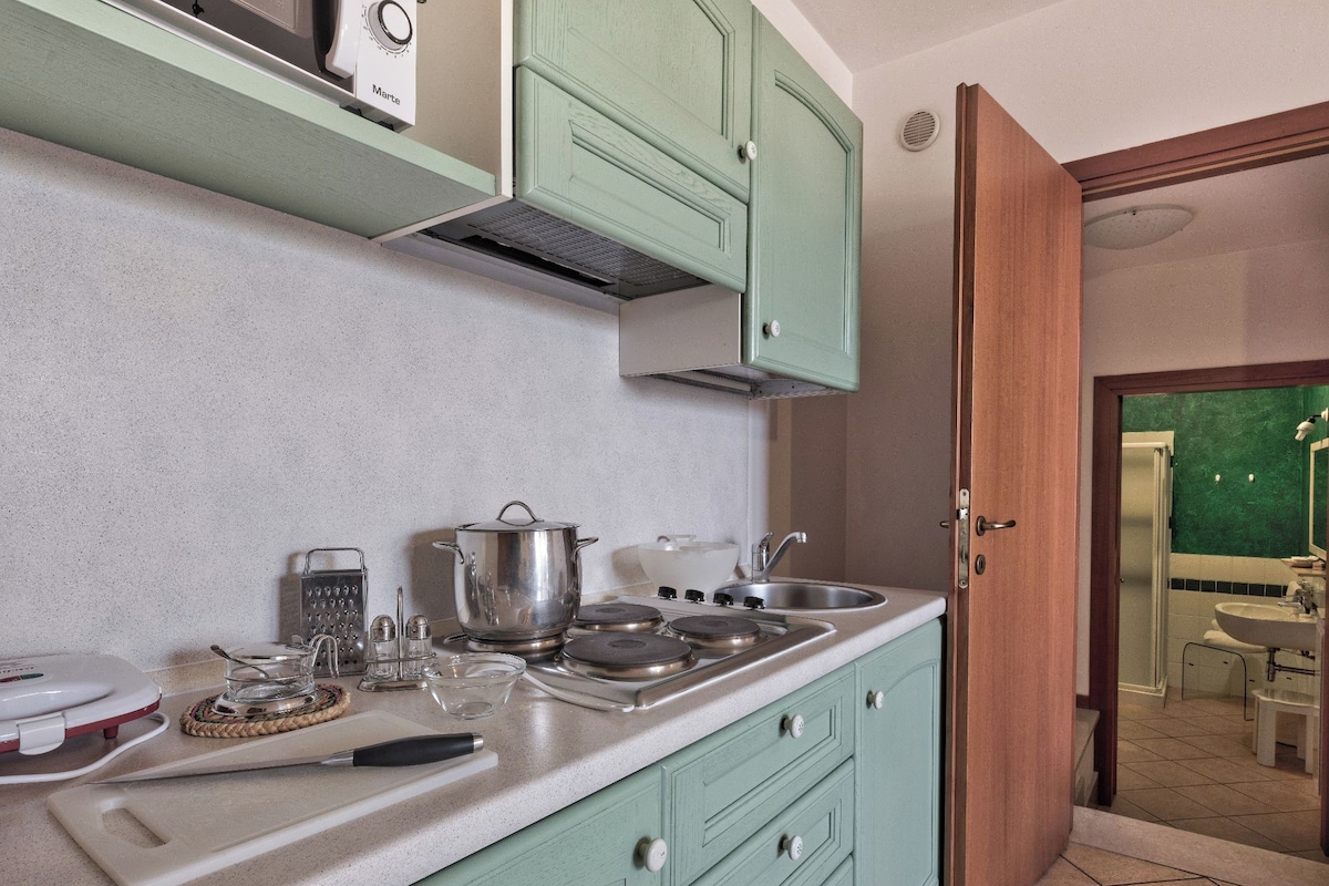 A kitchen with a stove, sink, and cabinets.