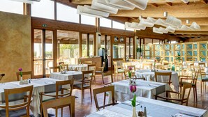 Un restaurante espacioso con vigas de madera, ventanas amplias y mesas dispuestas para comer.