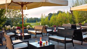 Un patio al aire libre con mobiliario de mimbre, mesas y sombrillas.
