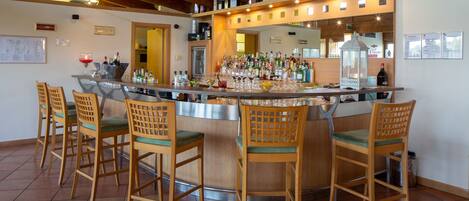 Eine Bar mit Holzhockern, einer Theke und verschiedenen Flaschen und Gläsern.