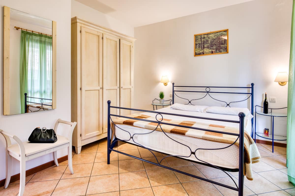 A bedroom with a bed, a chair, a wardrobe, and a painting on the wall.