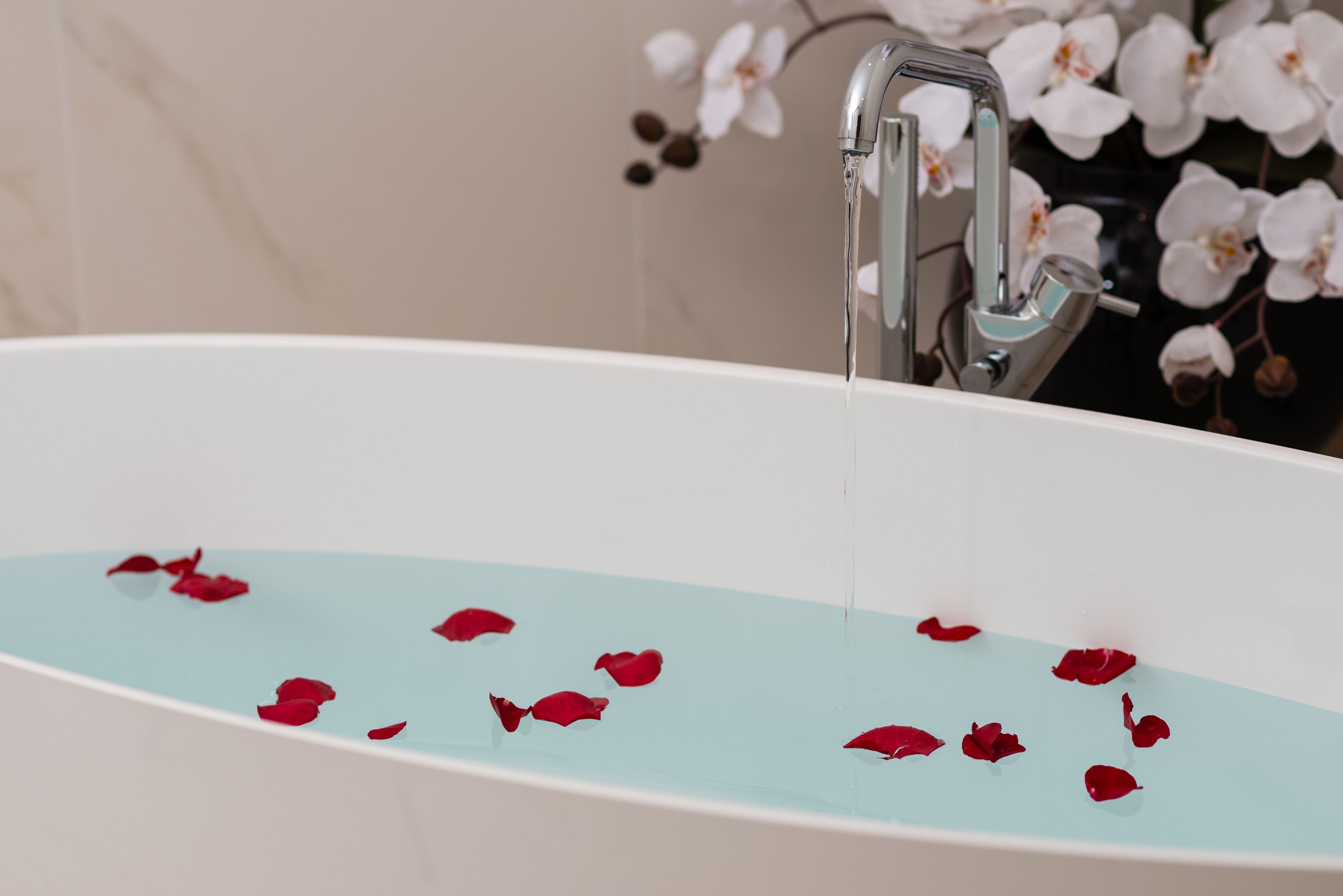 Una bañera con agua y pétalos de rosa.
