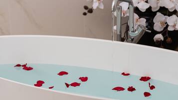 Una bañera con agua y pétalos de rosa.