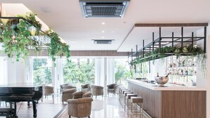 A modern bar area with a piano, bar stools, and a bar counter with shelves of bottles.