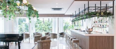 A modern bar area with a piano, bar stools, and a bar counter with shelves of bottles.