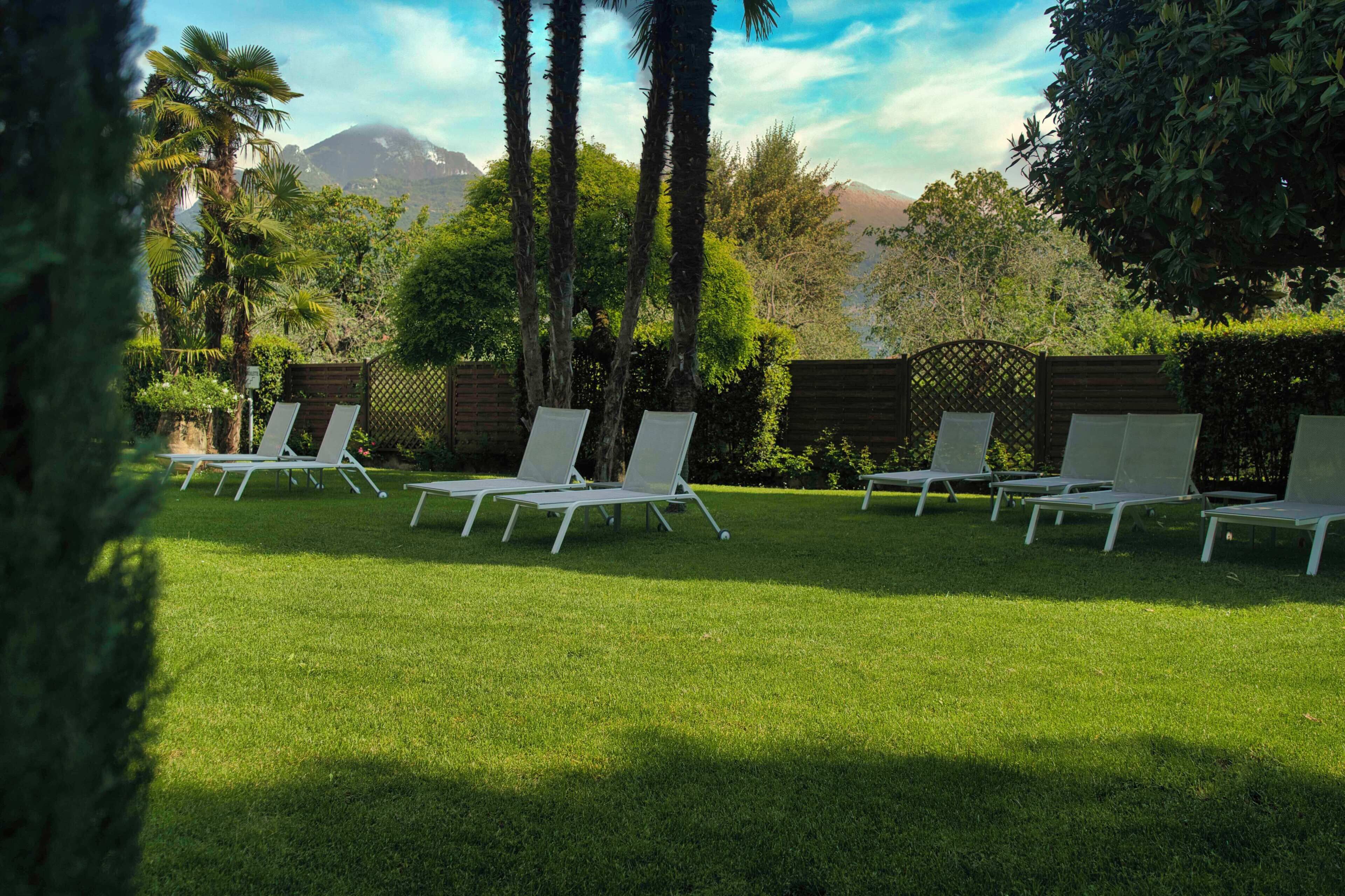 A well-maintained lawn with several white lounge chairs arranged in a row.