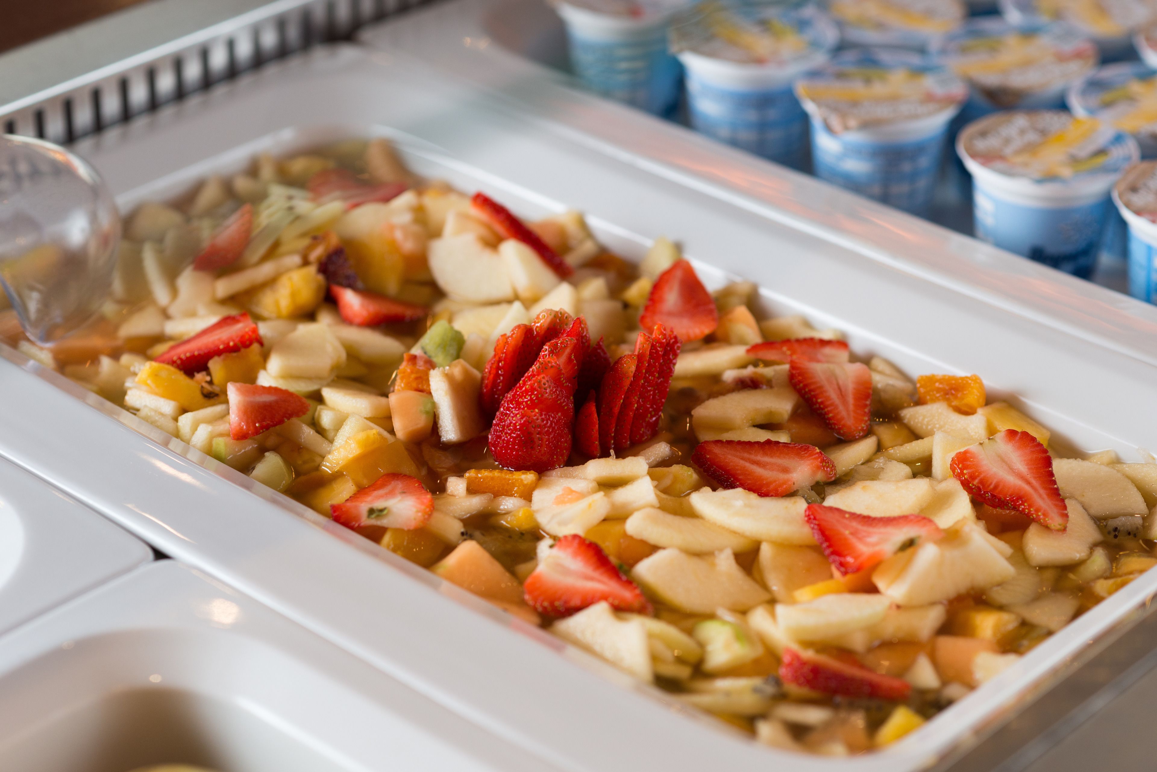 Ensalada de frutas con fresas y manzanas en un plato blanco.