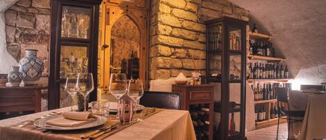 A dining area with a stone wall, a wine rack, and a table set for two.