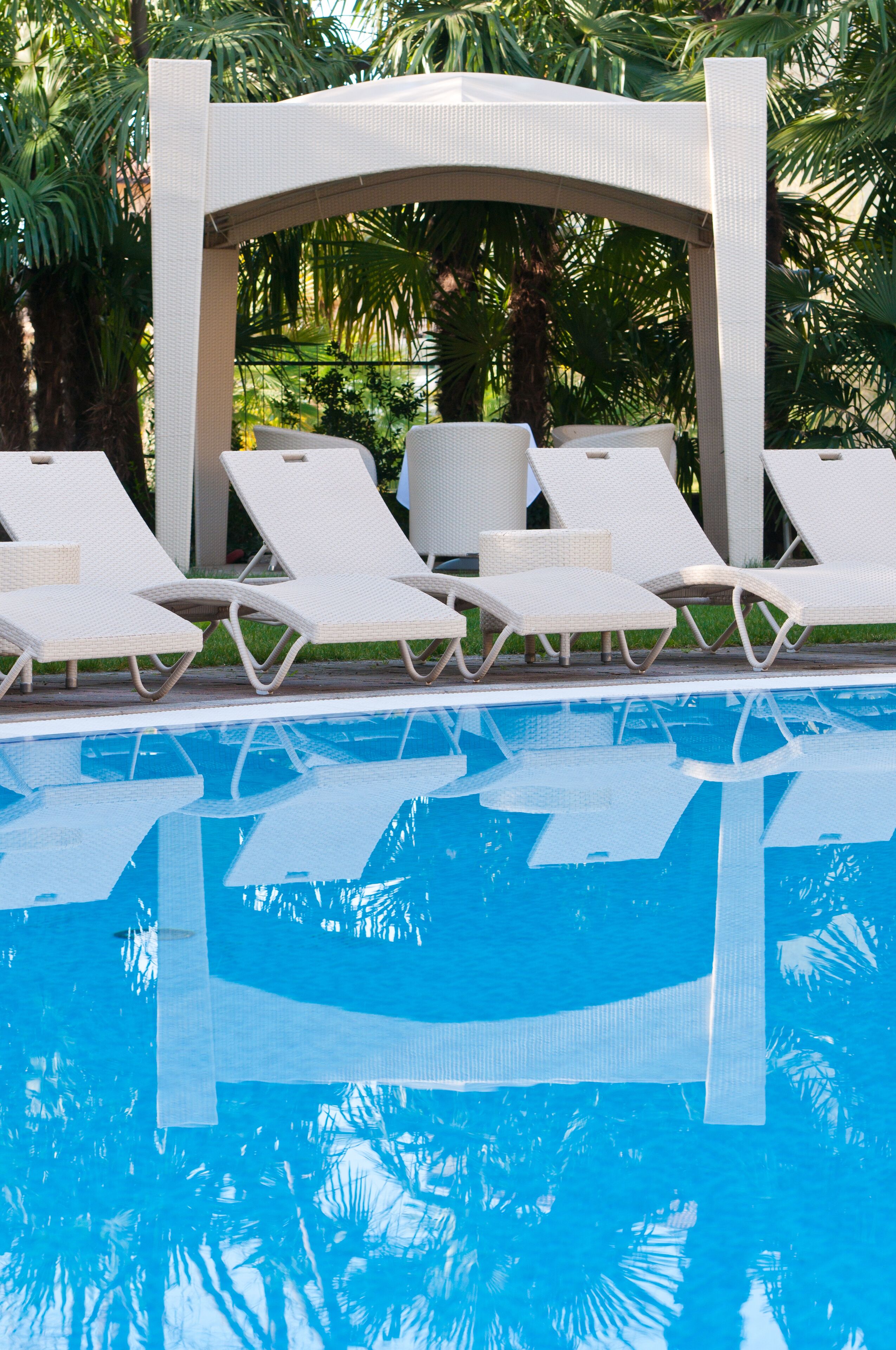 A poolside area with white lounge chairs and a canopy structure.