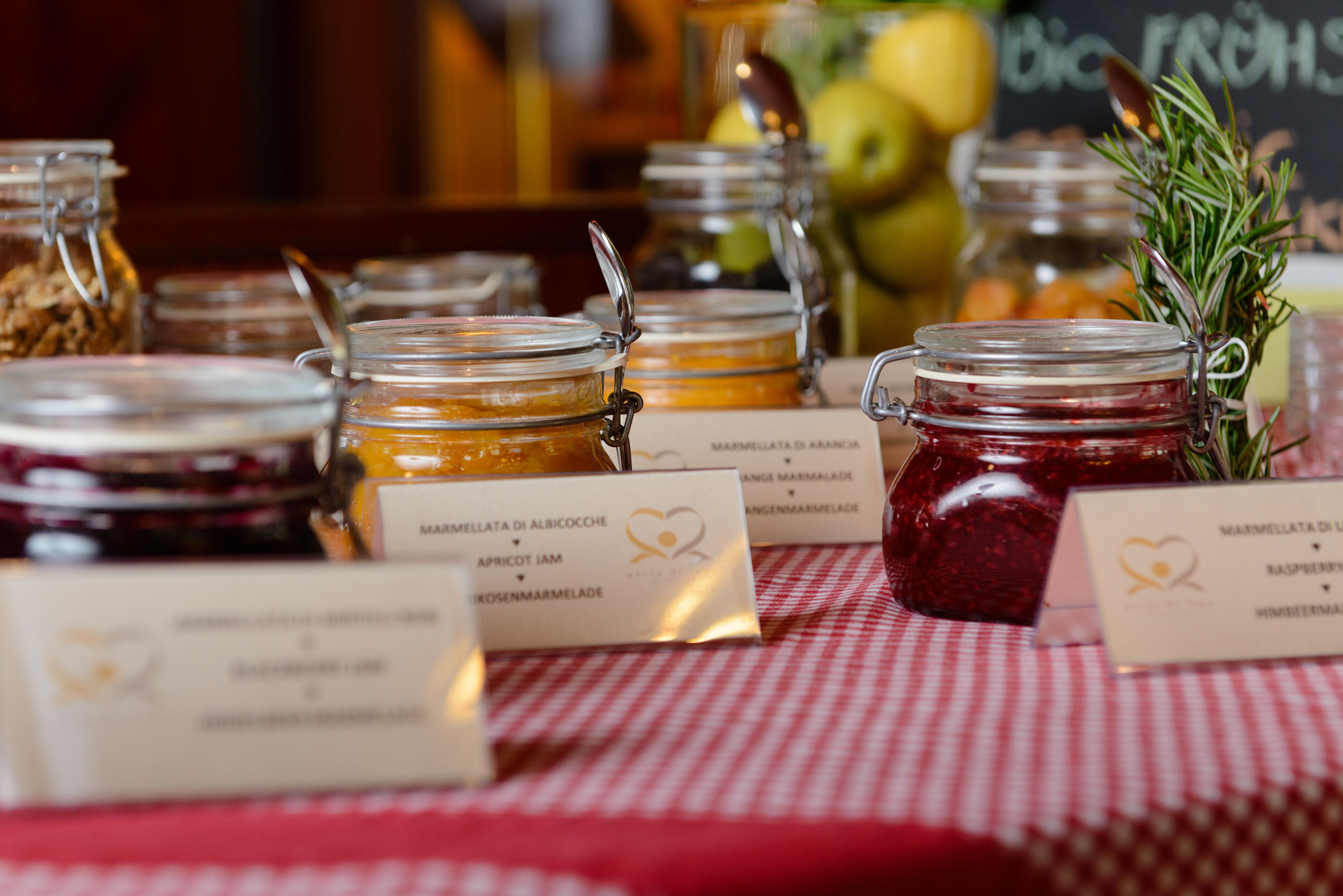Una mesa con botes de mermelada y confitura, cada uno etiquetado con el tipo de fruta.