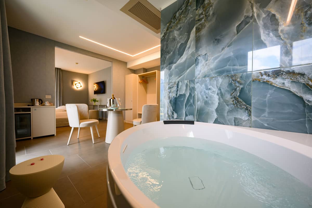 Un baño moderno con una bañera grande, paredes de mármol y un diseño minimalista.