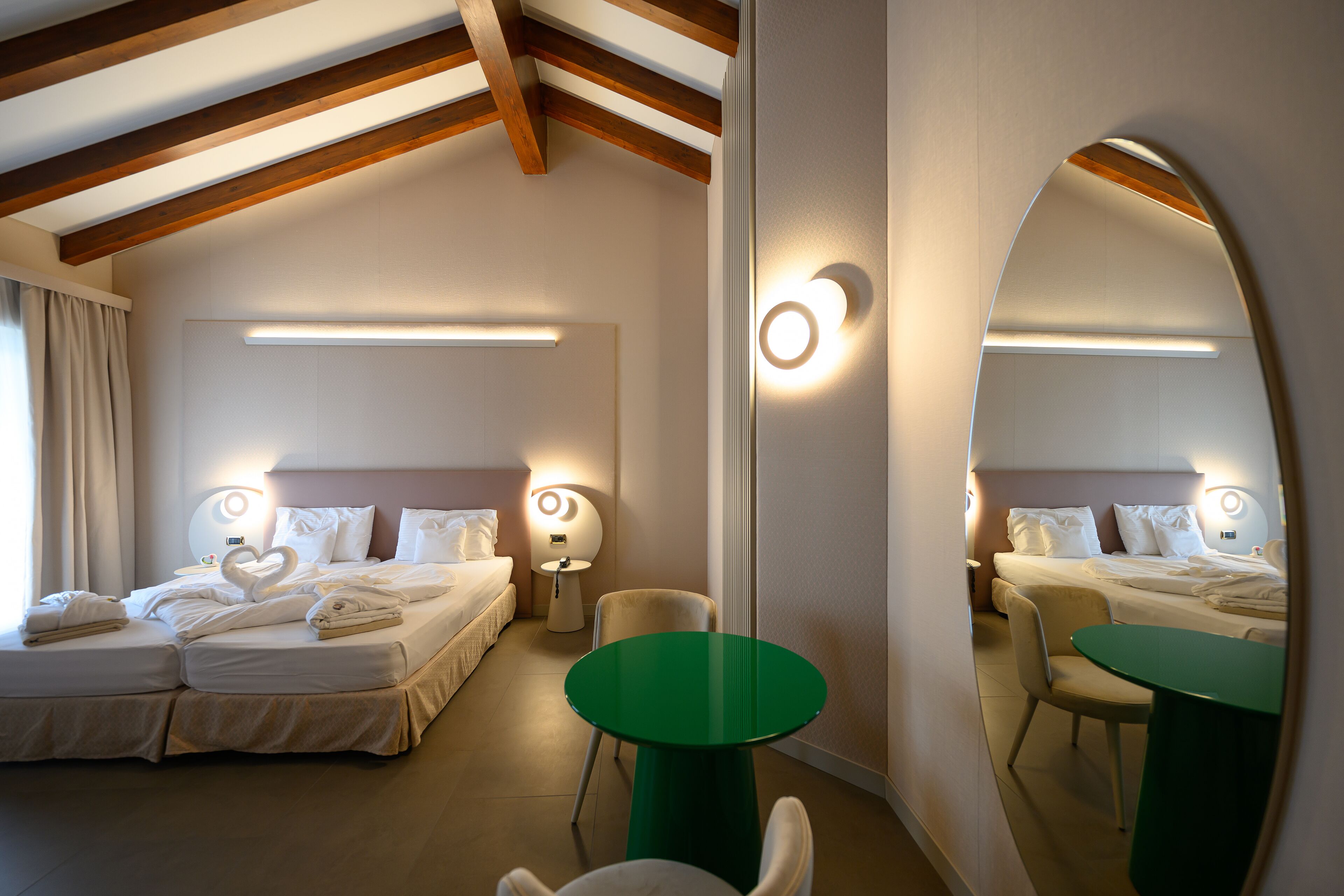 Une chambre d’hôtel avec un grand lit, une table verte et un miroir.