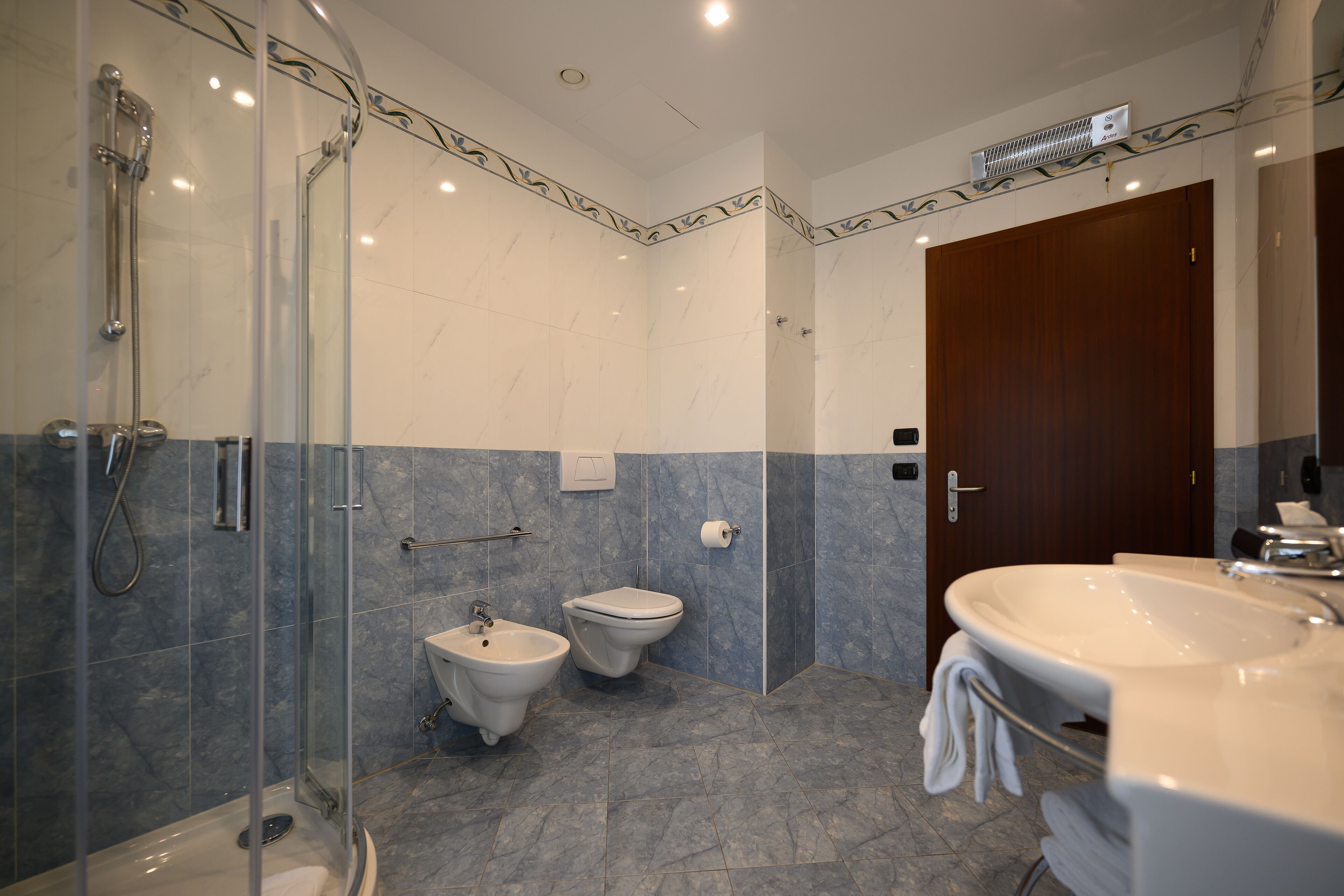 Une salle de bain moderne dotée d’une douche à parois de verre, d’un bidet, de toilettes et d’une grande baignoire avec un porte-serviettes.