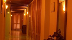 A hallway with wooden doors, a mirror, and a statue on a dresser. - La Casa del Duque (Osuna)