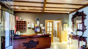 A reception area with a wooden reception desk, a clock, and a mirror. - La Casa del Duque (Osuna)