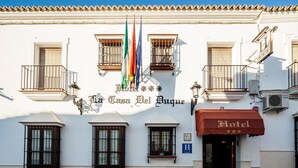 A hotel facade with balconies, a sign reading "Hotel La Casa Del Bague", and multiple flags. - La Casa del Duque (Osuna)
