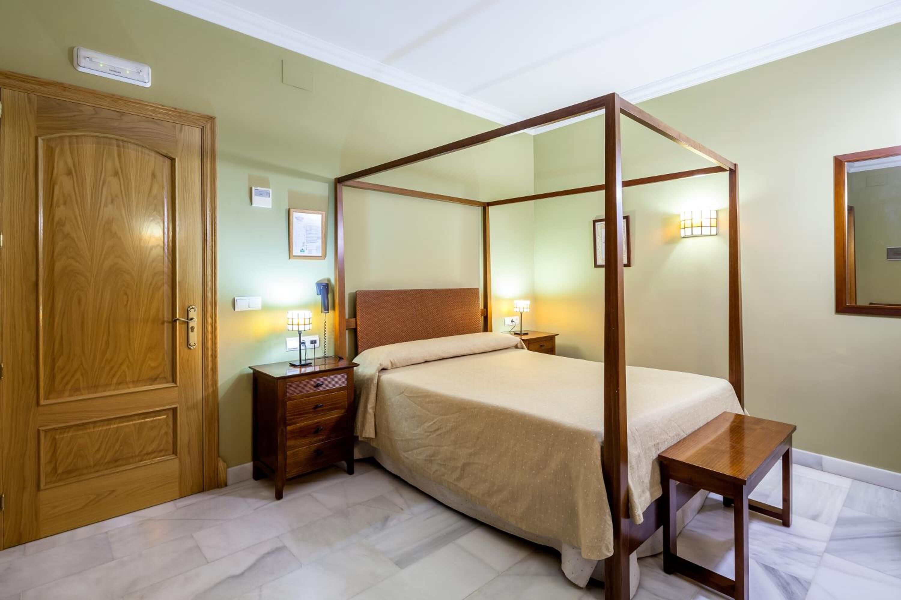 Una cama con dosel sobre un marco de madera, una mesita de noche y un armario de madera.